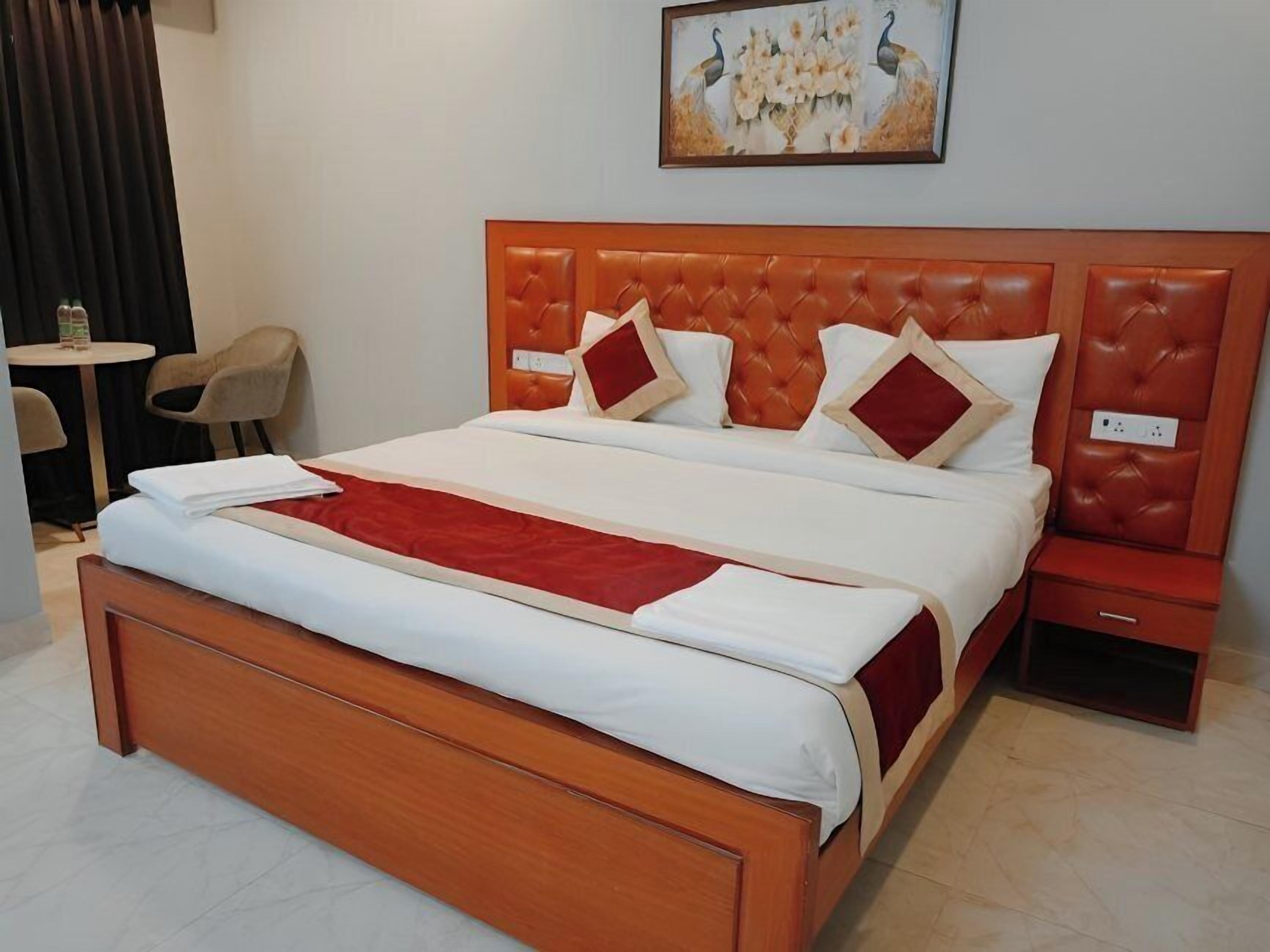 A hotel room with a large bed, a small table, and a chair.