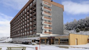 Ein mehrstöckiges Hotel mit modernem Design, das eine Kombination aus Balkonen und Fenstern zeigt.