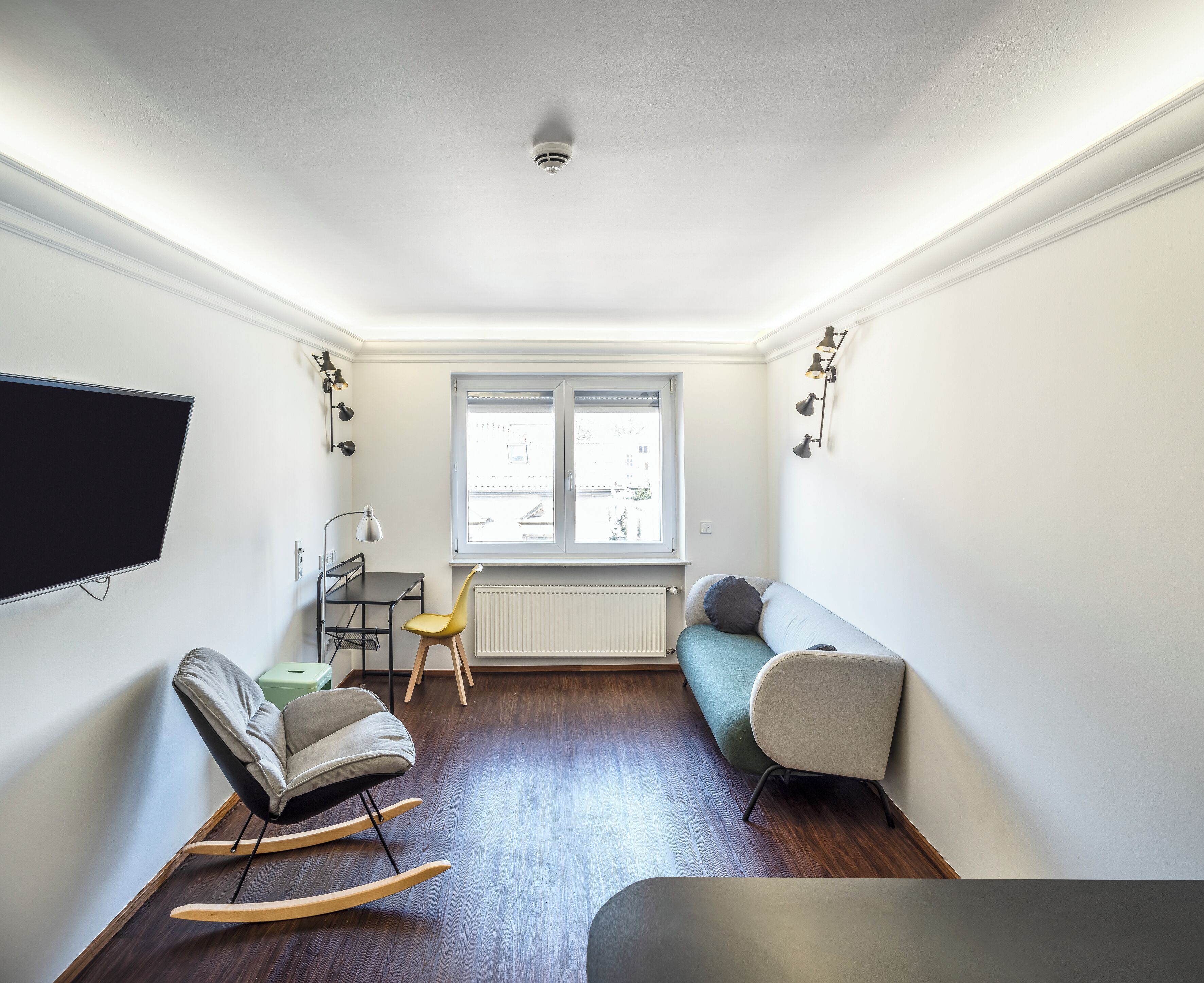 Una sala moderna con un sofá, una mecedora, una mesa y un televisor.