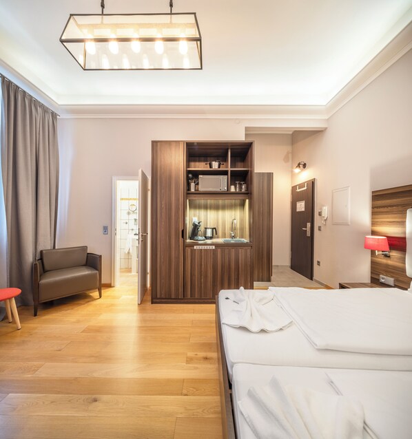 Una habitación de hotel con cama, zona de estar, kitchenette y baño.