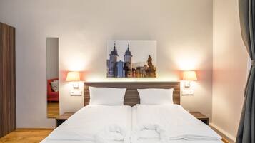 Ein Hotelzimmer mit einem ordentlich bezogenen Bett, zwei Nachttischlampen, einem Stadtbild an der Wand und einem Holzkopfende.
