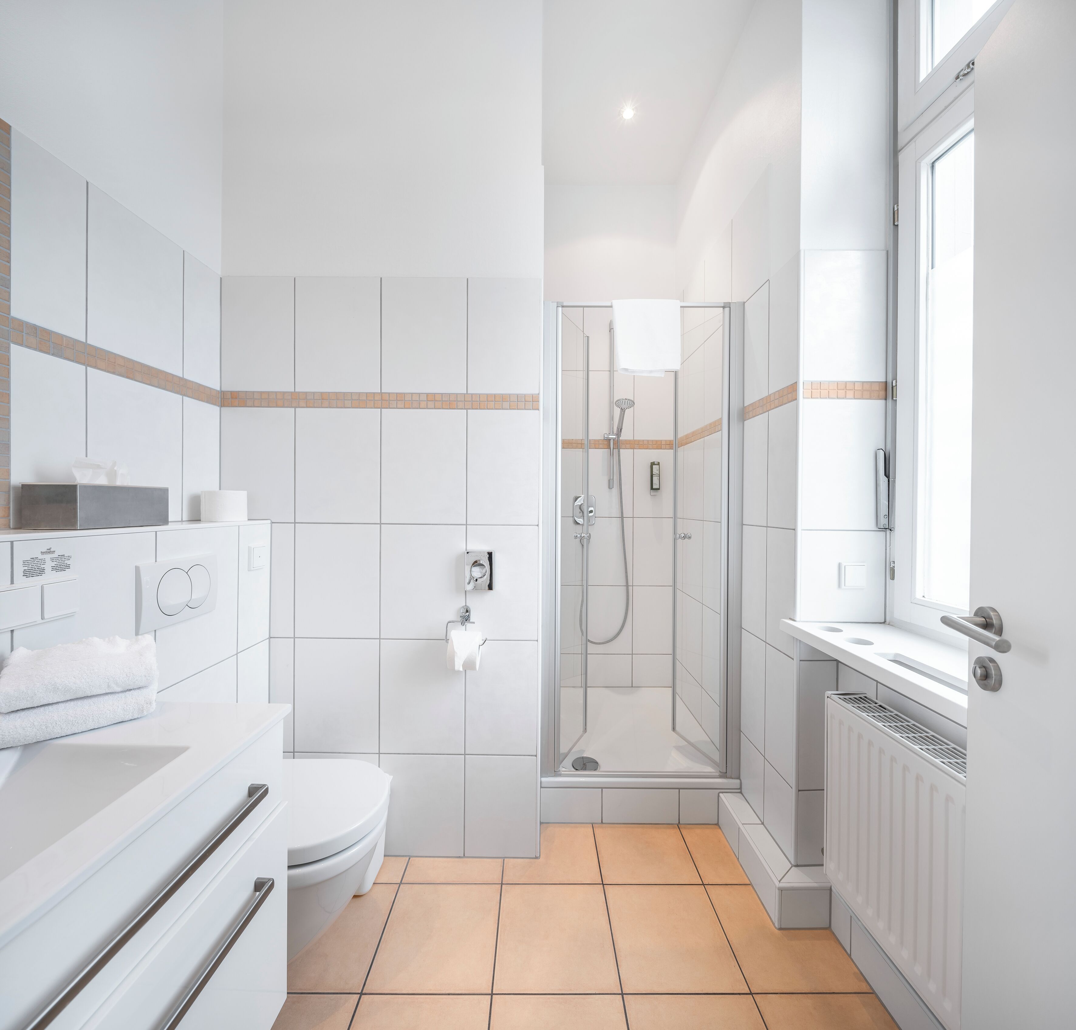 Une salle de bain moderne équipée de toilettes, d’un lavabo et d’une zone douche.