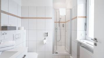 Une salle de bain moderne équipée de toilettes, d’un lavabo et d’une zone douche.