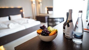 A hotel room with a bed, a bowl of fruit, and two bottles of water on a wooden table. - BoardingWorld Heidelberg (Heidelberg)