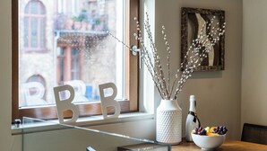 A dining area with a wooden table, a bowl of fruit, a vase with branches, and a bottle of wine. - BoardingWorld Heidelberg (Heidelberg)