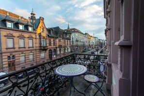 A balcony with wrought iron railings and two mosaic-topped tables, overlooking a street with historic buildings and a clear sky. - BoardingWorld Heidelberg (Heidelberg)