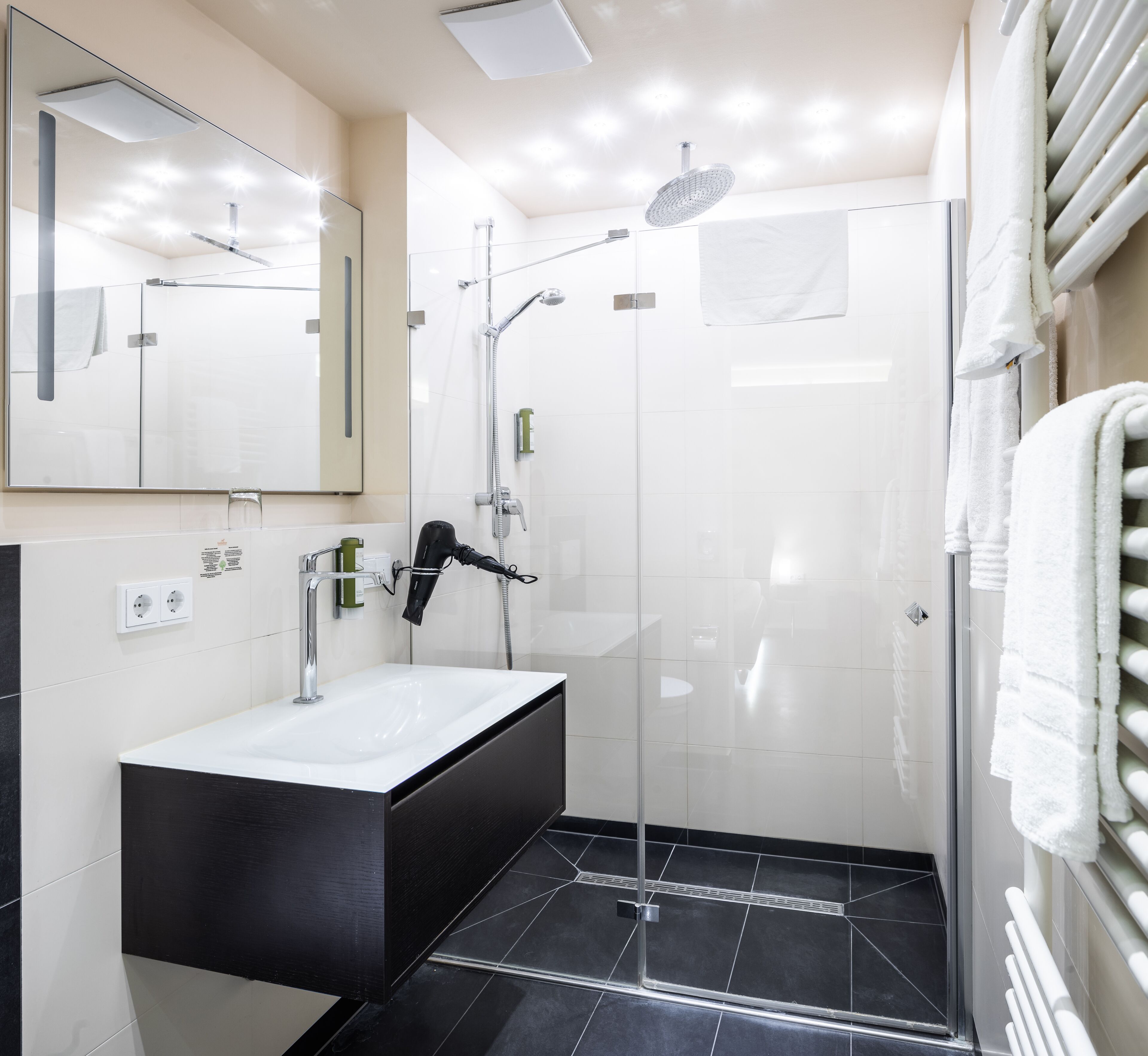A modern bathroom with a glass-enclosed shower, a standalone sink, and a large mirror.