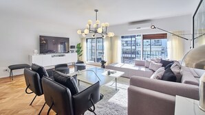 Una sala de estar moderna con comedor, televisor grande y vista a la ciudad.