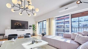 Una sala de estar moderna con sofá, mesa de centro, televisor y candelabro.