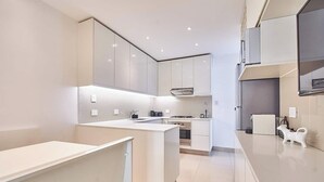 Una cocina moderna con armarios blancos, una isla central y electrodomésticos integrados.