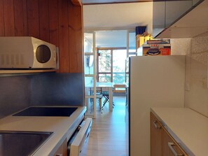 Efficient kitchenette with microwave and stove, adjacent to a dining area with table and chairs.