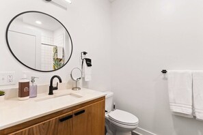 A bathroom with a round mirror, a sink, a toilet, and a towel rack.