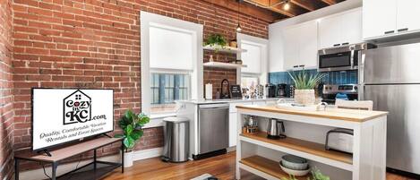 Una cocina moderna con pared de ladrillo, electrodomésticos de acero inoxidable y una mesa de comedor de madera.