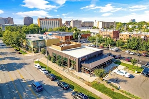 A parking lot with multiple cars, a building with a flat roof, and surrounding trees.
