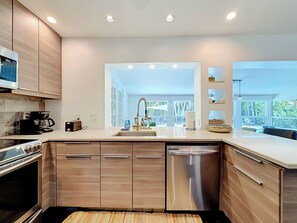 Une cuisine moderne dotée d’appareils électroménagers intégrés, d’une grande fenêtre et offrant une vue sur l’extérieur.