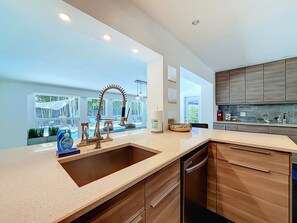 A modern kitchen with a large island, built-in appliances, and a view to the outdoors. - Modern Coastal Home Near Las Olas + Heated Pool (Fort Lauderdale)