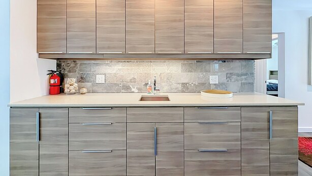 A modern kitchen with wooden cabinets, a marble backsplash, and a built-in oven. - Modern Coastal Home Near Las Olas + Heated Pool (Fort Lauderdale)