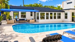 A swimming pool with lounge chairs and a covered seating area. - Modern Coastal Home Near Las Olas + Heated Pool (Fort Lauderdale)
