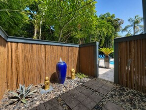 A bamboo fence with a blue vase and golden statues in a garden area.