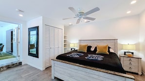 A bedroom with a bed, bedside tables, a ceiling fan, and a view through an open door. - Modern Coastal Home Near Las Olas + Heated Pool (Fort Lauderdale)