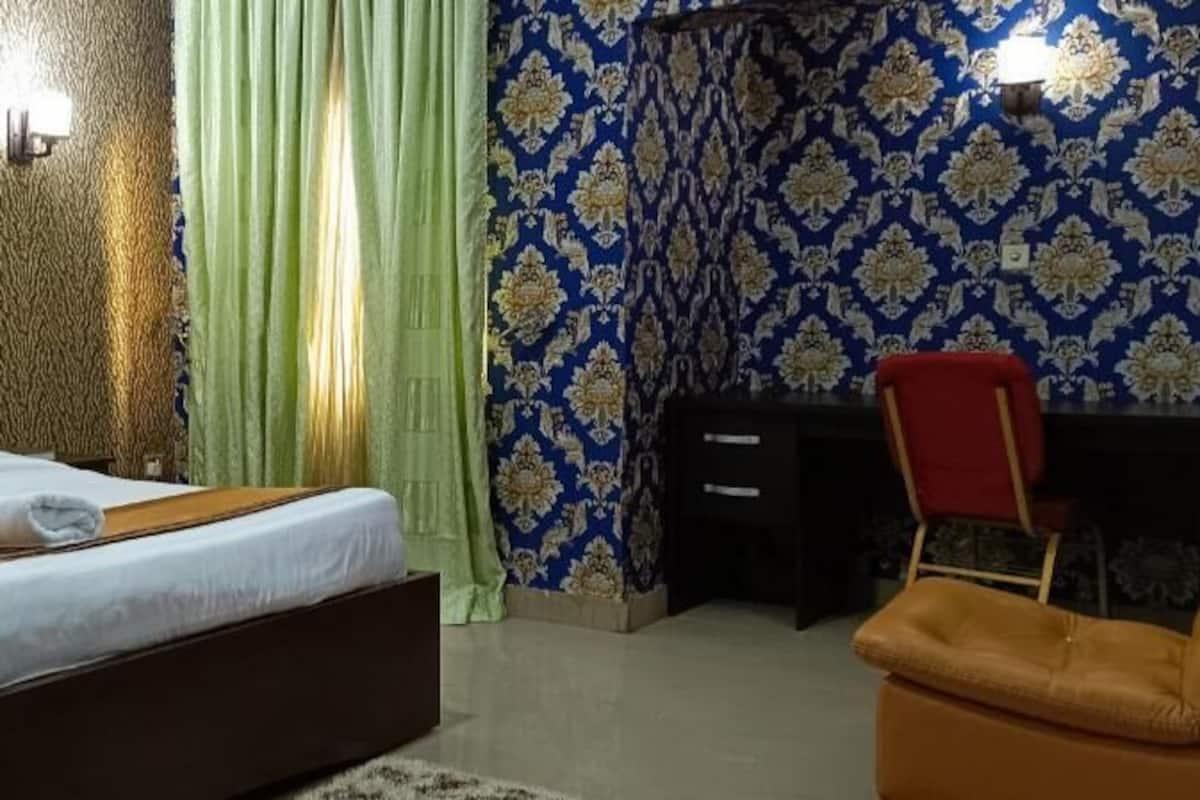 Een hotelkamer met een bed, een bureau, een stoel en gordijnen.