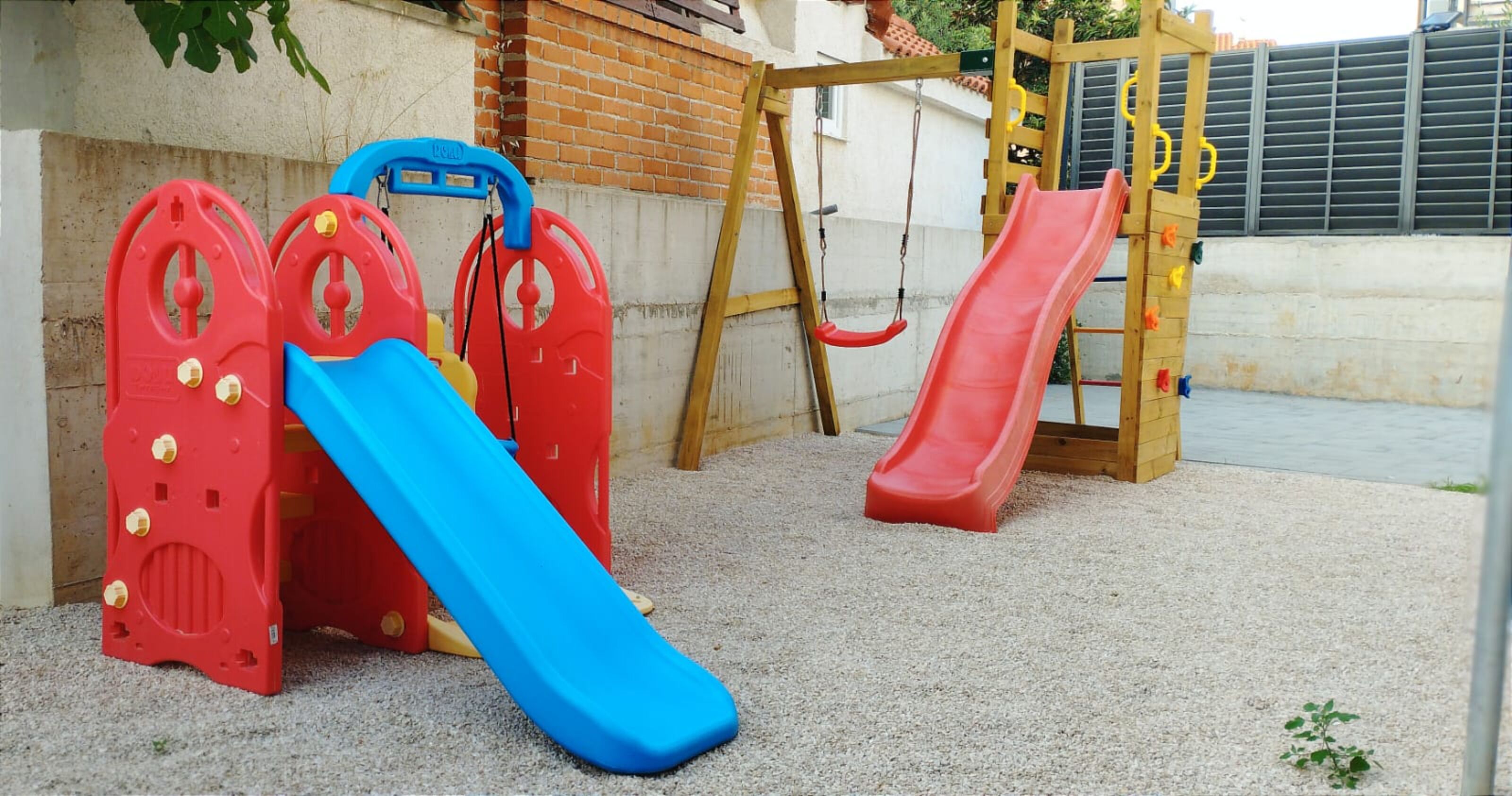 Zona de juegos infantiles con tobogán, estructura para escalar y columpios.