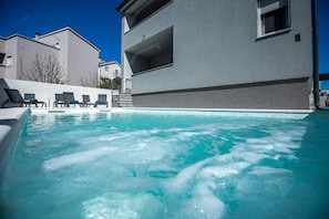 Una piscina al aire libre de temporada, sombrillas, tumbonas