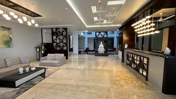 Un salón espacioso con piso de mármol, un sofá, una mesa de centro y una lámpara moderna.