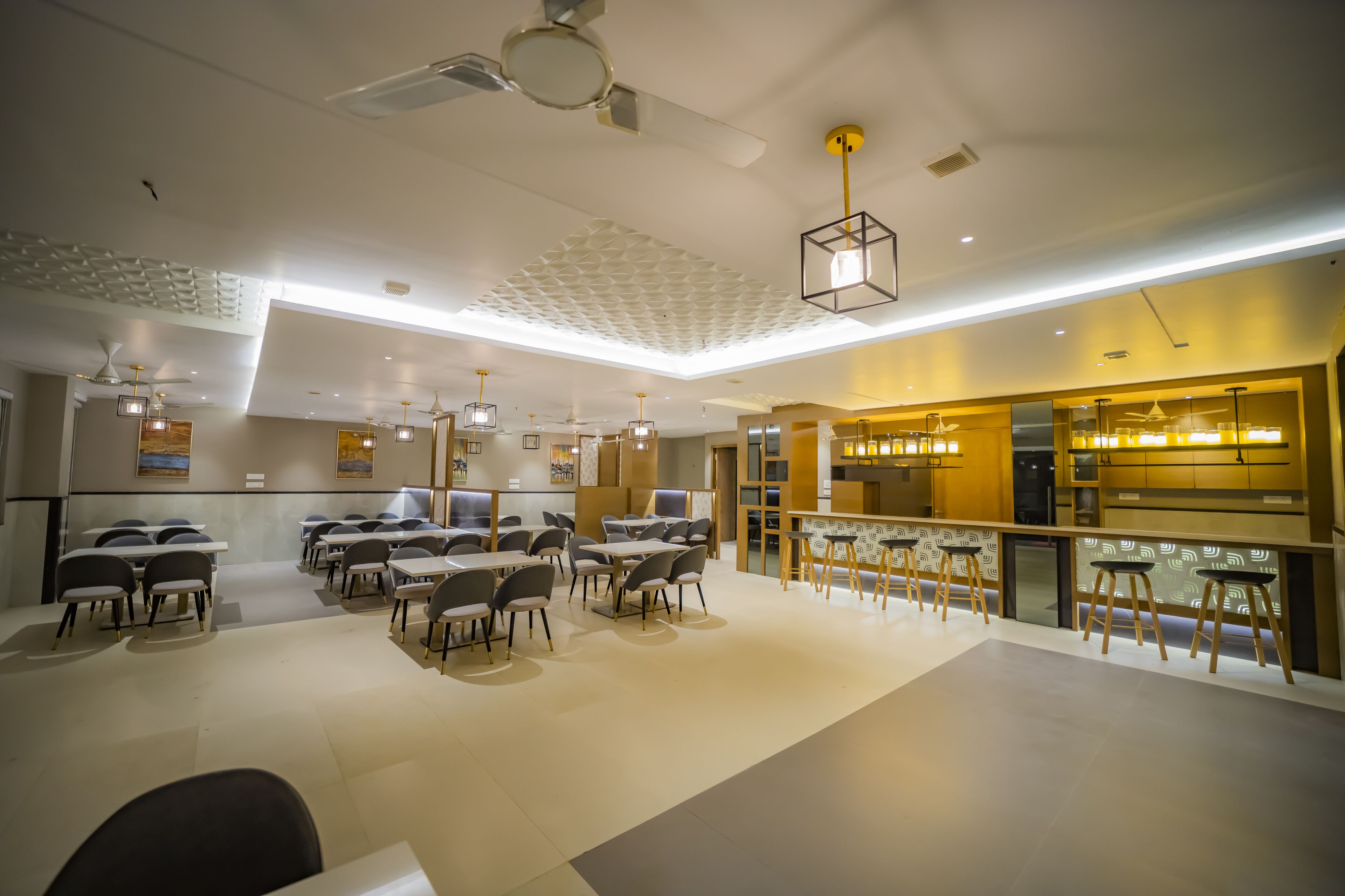A modern dining area with tables and chairs, ceiling fans, and pendant lighting.