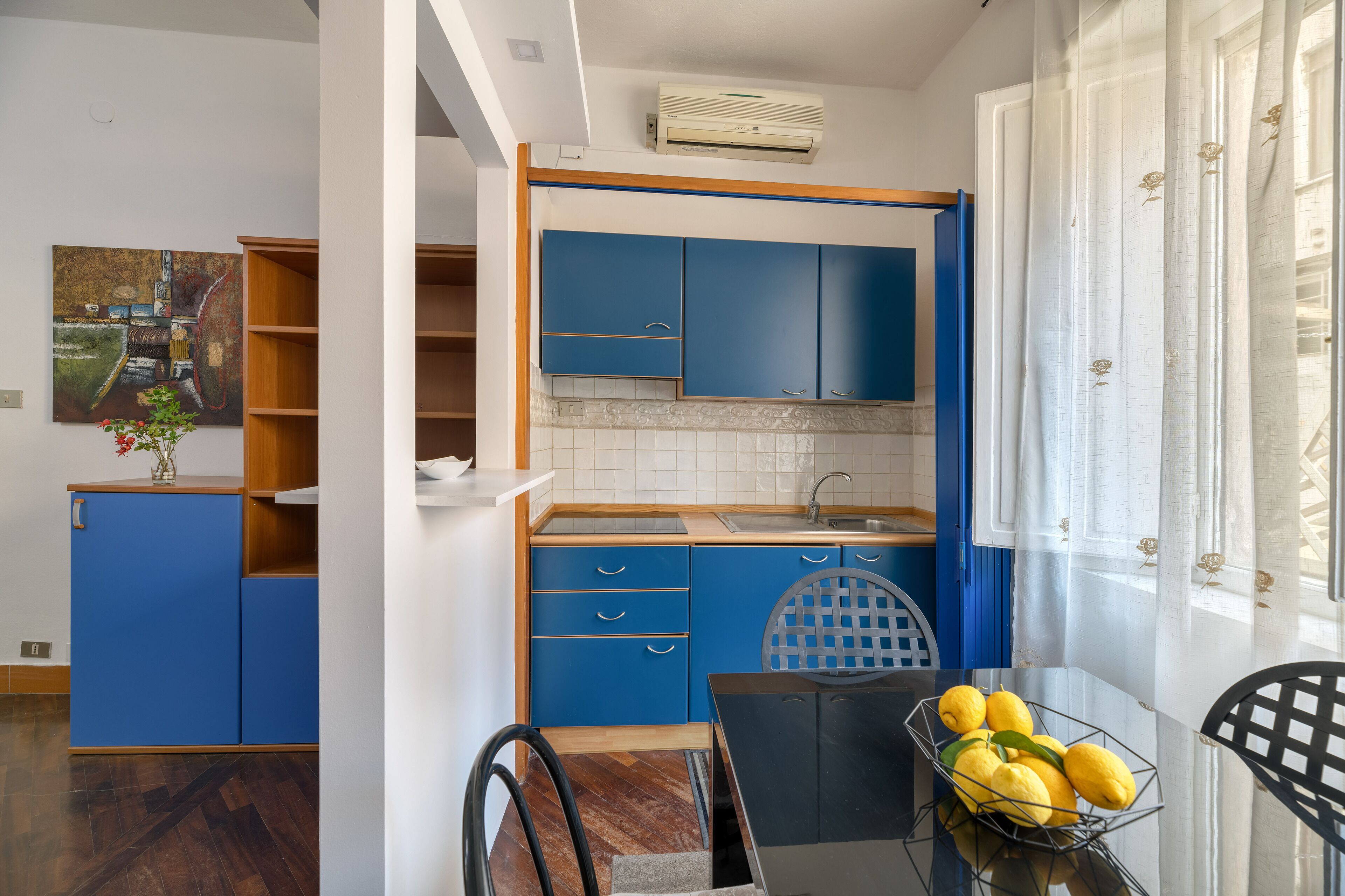 A modern kitchen with blue cabinets, a sink, and a dining area with a table and chairs.