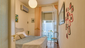 Un dormitorio con cama, una silla, una mesa y una ventana.