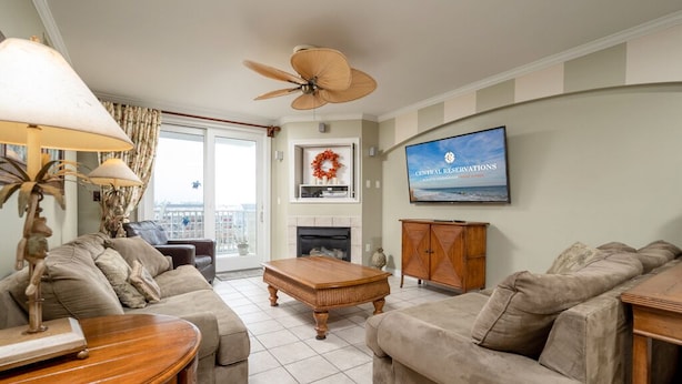 A living room with a sofa, armchair, coffee table, and a television mounted on the wall.