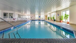 An indoor swimming pool with clear lanes, a tiled floor, and a ceiling with horizontal beams.