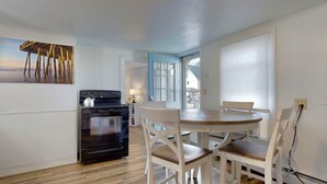 Een keuken met een fornuis, oven en een eettafel met stoelen.