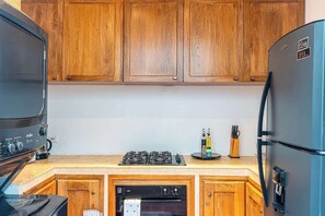 A compact kitchen with wooden cabinets, a gas stove, a built-in oven, and a refrigerator. - Room distribution (All bedrooms in the first floor):<br>Room 1- Queen Bed / Single Bed<br>Room 2- Queen Bed / Single Bed<br>Room 3- Queen Bed (Cartagena de Indias)