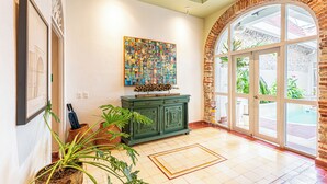 Eine geräumige Lobby mit einem grünen Schrank, einem farbenfrohen abstrakten Gemälde und einer großen, bogenförmigen Glasdoor zur Außenwelt.