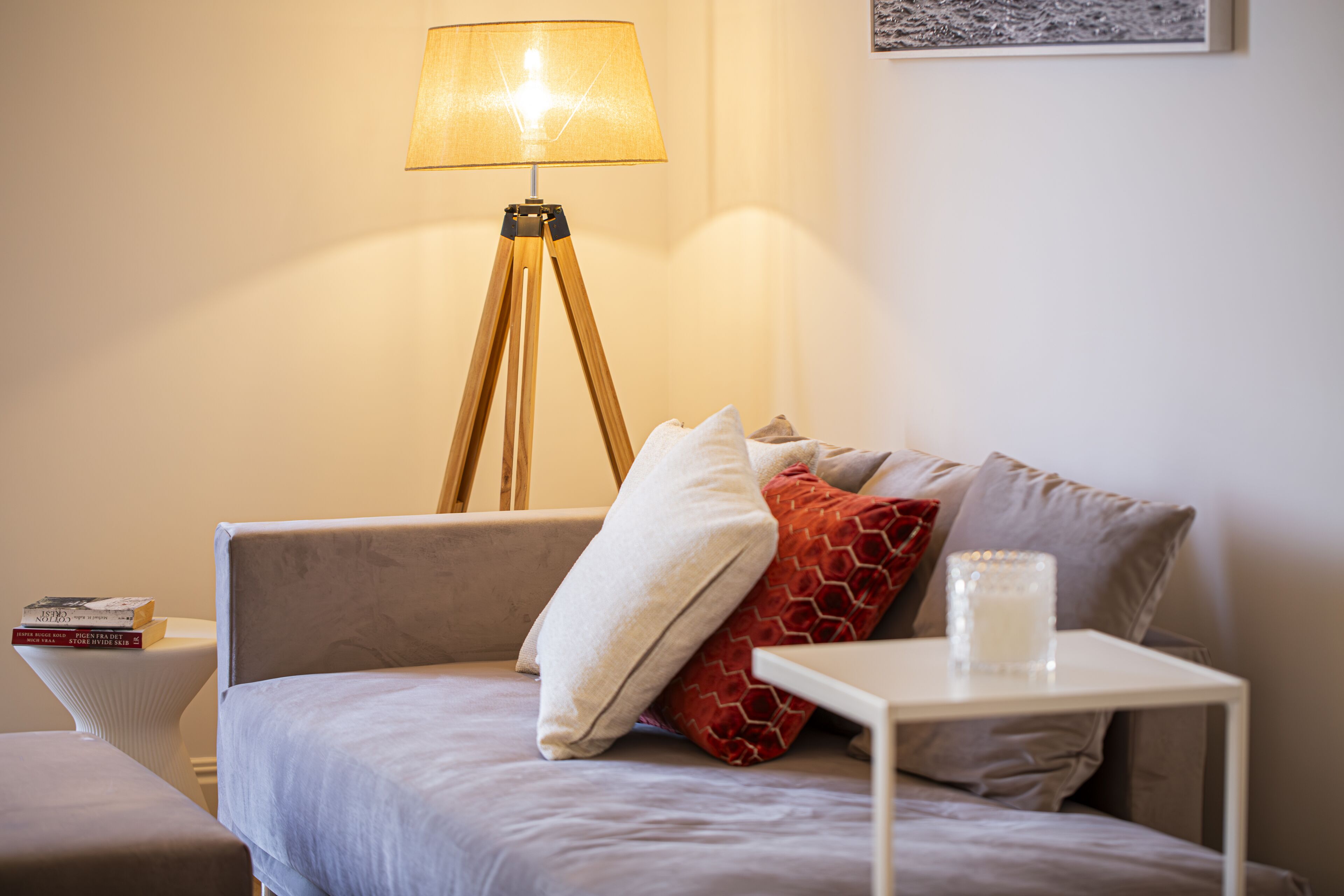 A modern bedroom with a bed, bedside table, lamp, and a small white table with a candle.