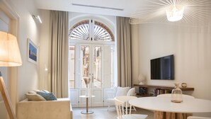 Una sala de estar moderna con un sofá, una mesa redonda de comedor y un televisor montado en la pared.