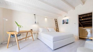 Un dormitorio con cama, escritorio, silla, escalera y una pequeña mesa con una planta.