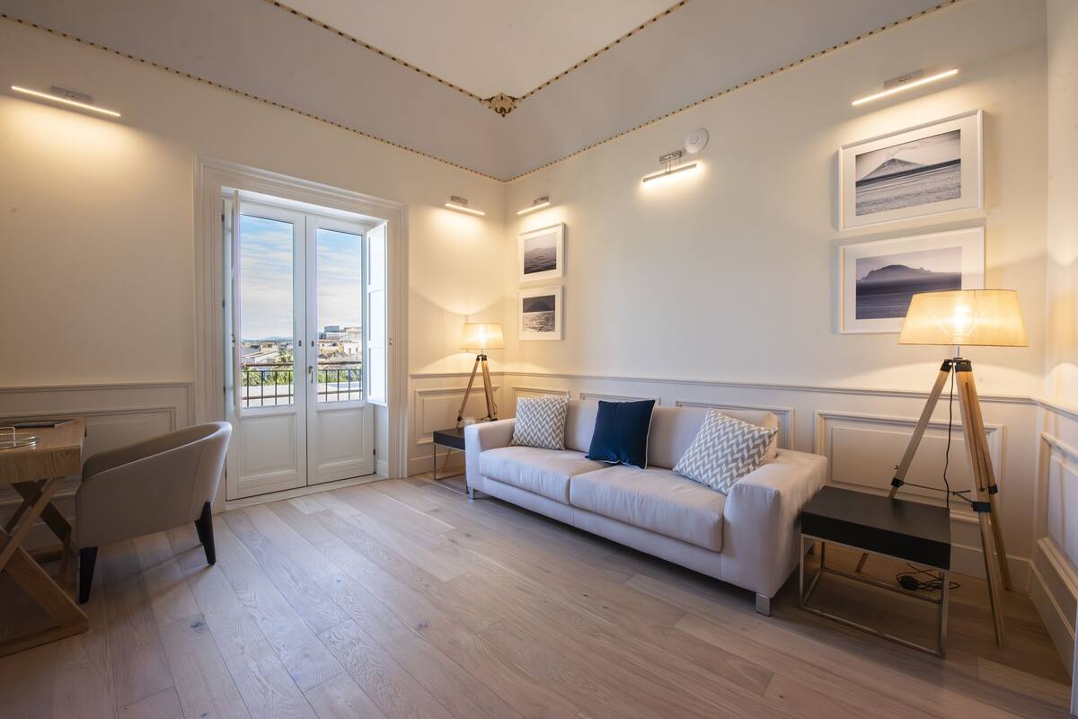 Un salon moderne avec un canapé blanc, un bureau et un lampadaire sur trépied.