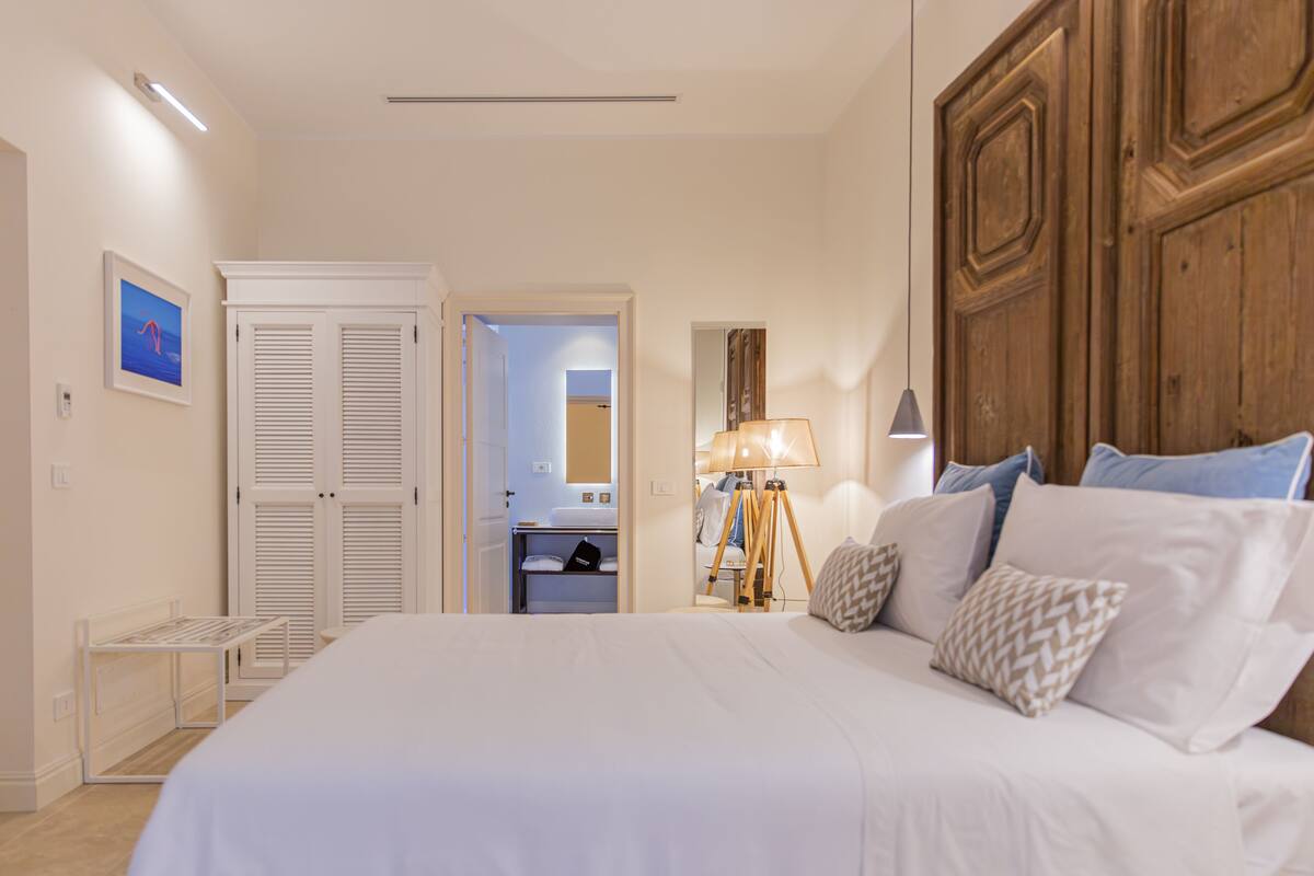 Une chambre à coucher avec un grand lit, une armoire en bois, une lampe de chevet et une petite table.