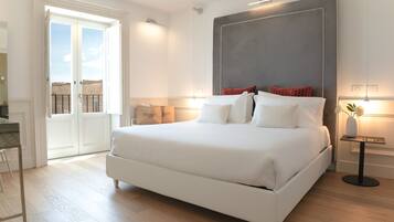 A modern bedroom with a large bed, a bedside table, a chair, and a view of the outside balcony.