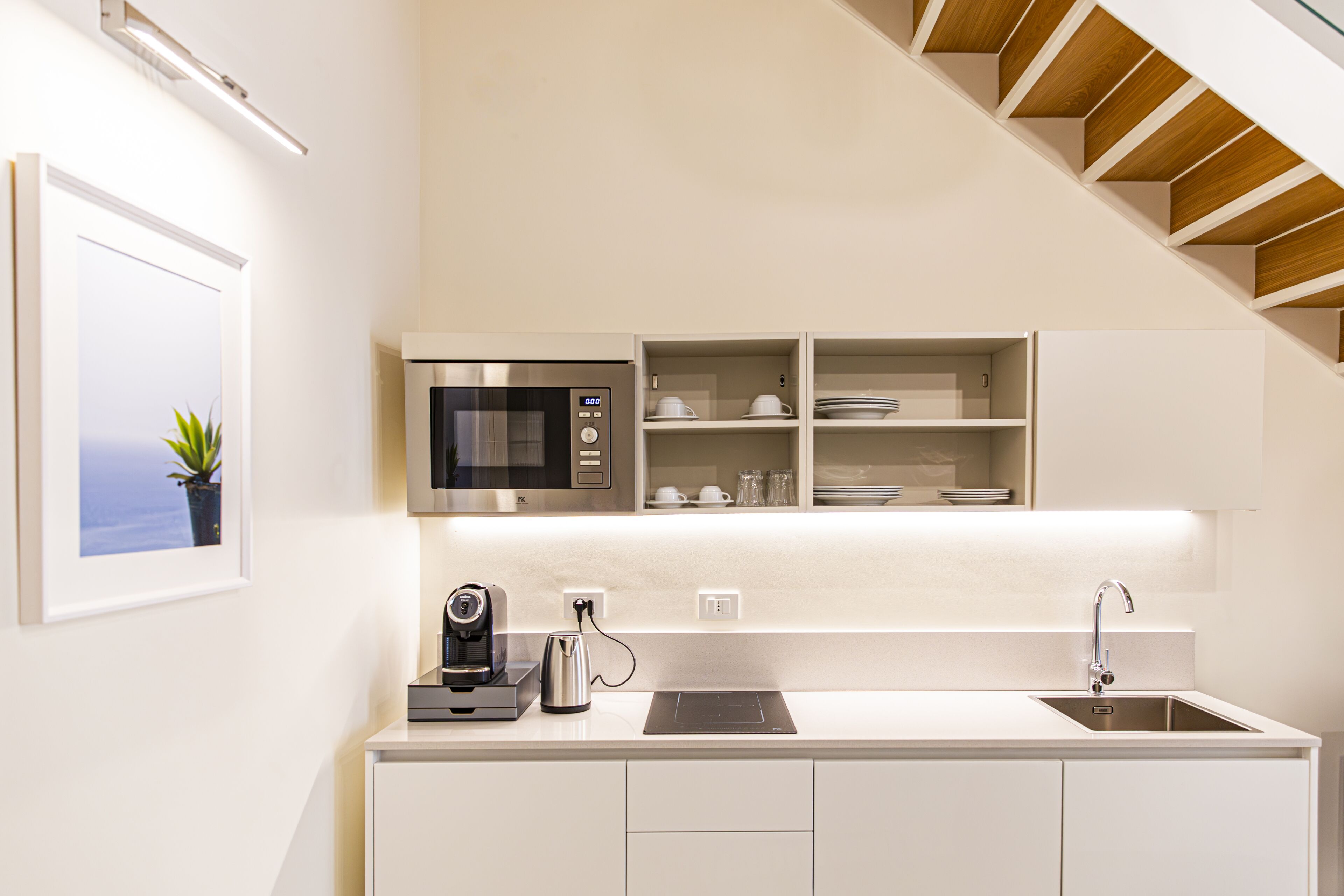 A modern kitchen with a built-in microwave, coffee maker, and sink.
