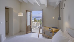 Un dormitorio con una cama grande, un escritorio de madera y vistas al exterior.