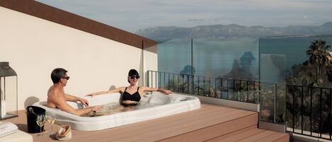 A hot tub on a balcony with a view of the sea and mountains.