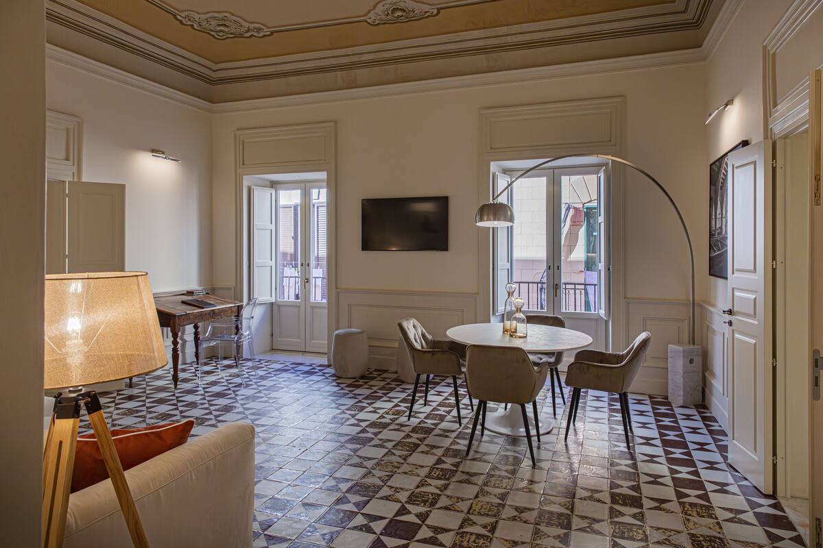 Un coin repas avec une table ronde, des chaises, une lampe et un sol à motifs.