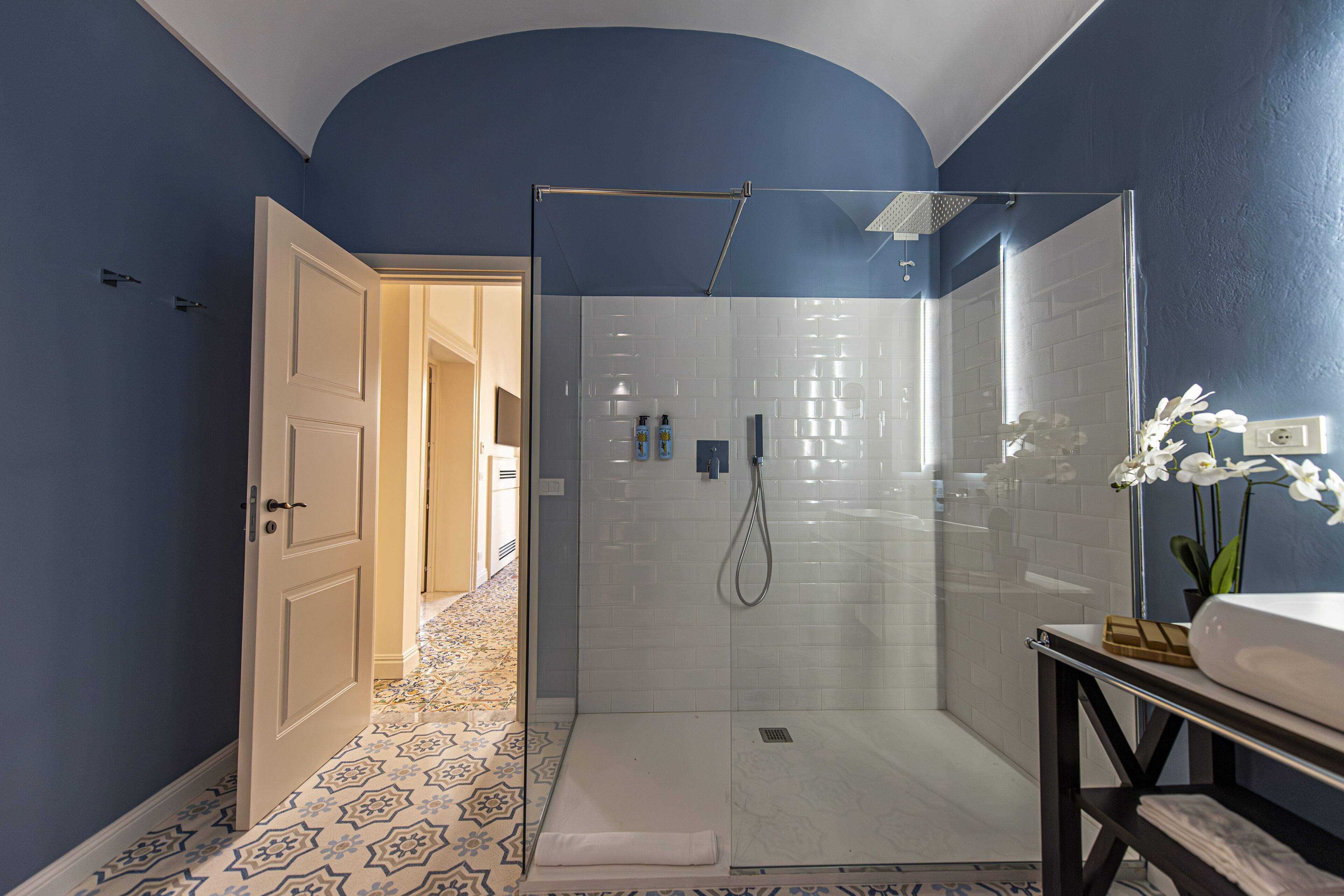 Une salle de bain moderne avec une douche à parois de verre, un lavabo blanc et un carrelage décoratif.