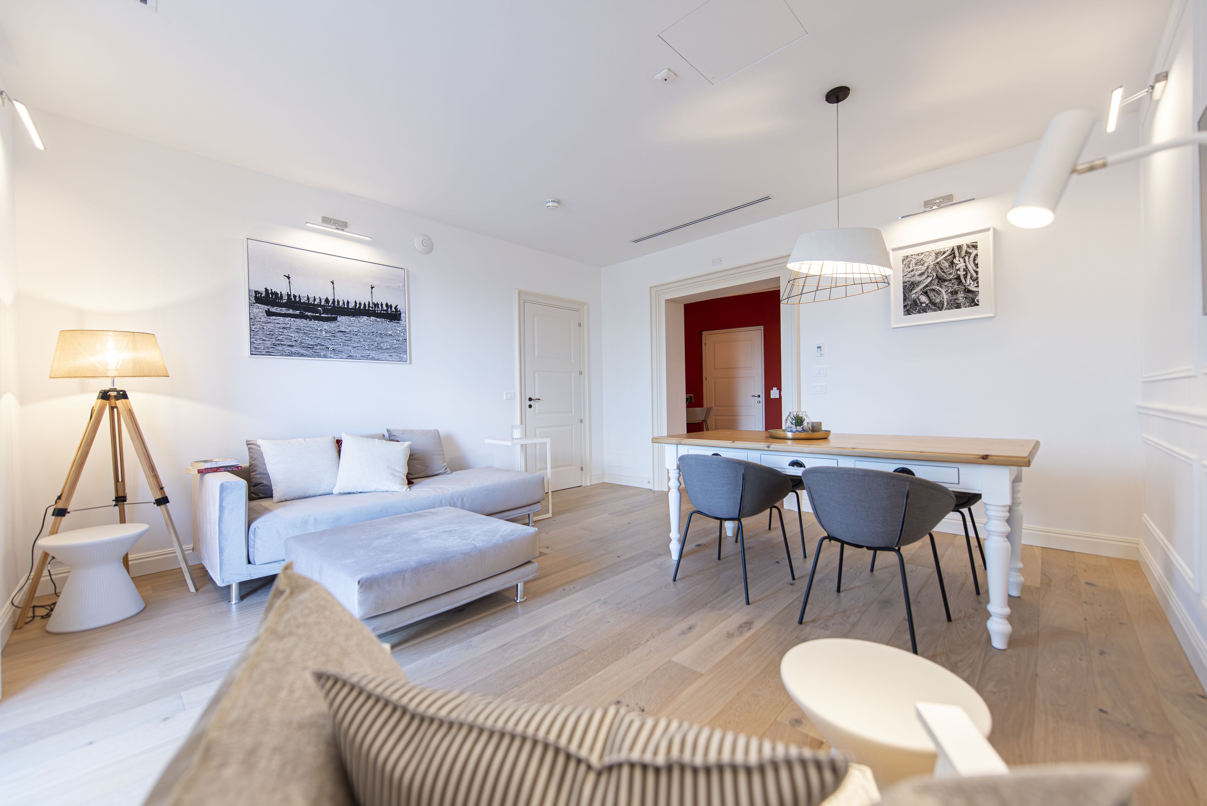 Ein modernes Wohnzimmer mit einer Couch, einem Esstisch mit Stühlen, einer Lampe und Kunstwerken an den Wänden.