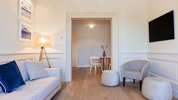 Una sala de estar moderna con un sofá, otomanas, una lámpara y un comedor con sillas y una mesa.