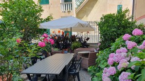Une terrasse extérieure avec une table et des chaises, entourée de plantes et de fleurs en pot.
